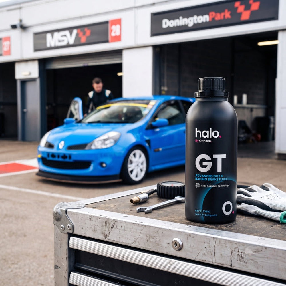Halo GT DOT 4 racing brake fluid bottle on a toolbox in the Donington Park pit lane with a Renault Clio race car